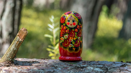 Russian Nesting Doll on a Log in a Forest on a Sunny Day