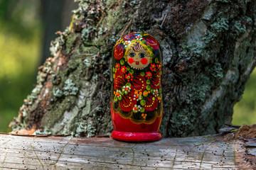 Russian Nesting Doll on a Log in a Forest on a Sunny Day