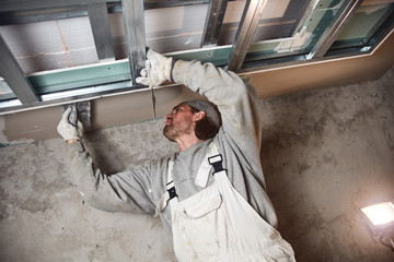 Construction worker plastering gypsum walls inside the house.