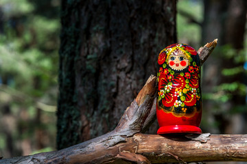 Russian Nesting Doll on a Log in a Forest on a Sunny Day