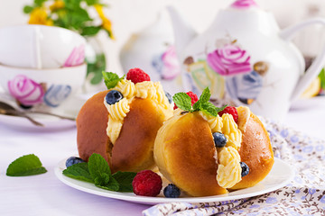 Rum baba decorated with whipped cream and fresh raspberry, blueberry. Savarin with rum, cream and berries. Italian cuisine