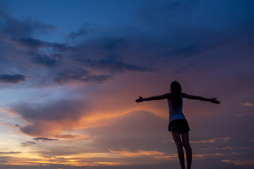 Fototapeta premium Silhouette of free woman enjoying freedom feeling happy at sunset. Serene relaxing woman in pure happiness