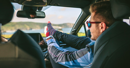 Young man resting with his feet up sitting on the passenger seat of the car