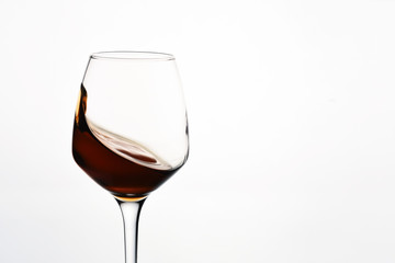 Glass with a splash of red wine on white background close-up
