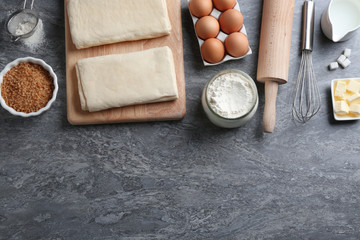 Fototapeta na wymiar Puff pastry dough and ingredients on grey table, flat lay. Space for text