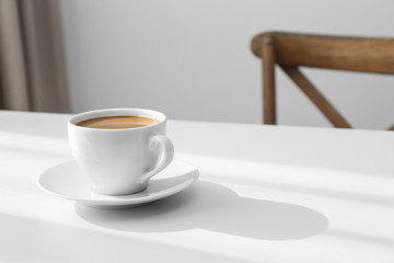 Cup of hot aromatic coffee on white table indoors. Space for text