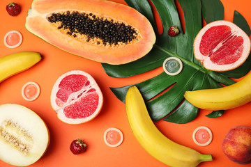 Flat lay composition with condoms and exotic fruits on orange background. Erotic concept