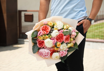 Young man with beautiful flower bouquet outdoors, closeup view. Space for text