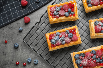 Fresh delicious puff pastry with sweet berries on grey table, flat lay. Space for text