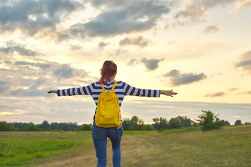 Young girl with yellow backpack, her back with open hands
