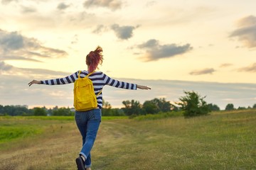 Young girl with yellow backpack, her back with open hands