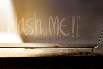 Write the words "wash me" on the very dirty surface of the car. Concept car wash.