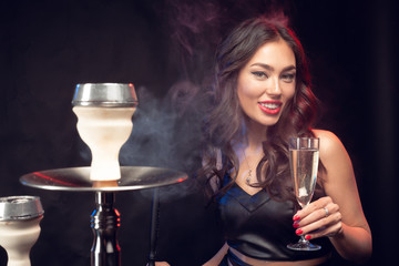 Nice woman smoking shisha and drinking cocktail in a bar