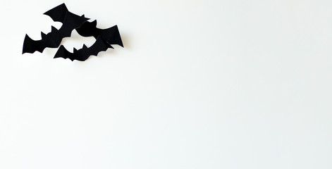 Halloween and decorating concept - black paper bats made from velvet paper fly over a white background.