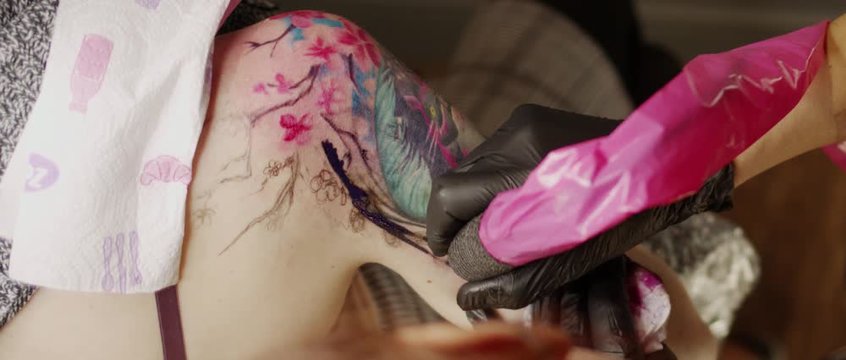 Tattoo master makes tattoo girl on shoulder