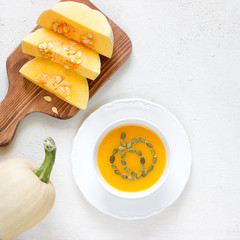 Pumpkin soup with parsley on a white wooden background