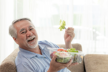 Lifestyle senior man feel happy enjoy eating diet food fresh salad on sofa