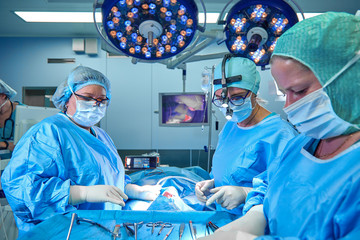 A surgeon's team in uniform performs an operation on a patient at a cardiac surgery clinic. Modern...