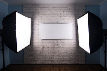 studio lighting, white monitor on a white brick wall