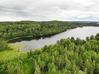Fototapeta na wymiar Aerial view of lake and green forest on a summer day in Finland. Drone photography