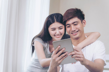 Young pretty woman and handsome man lying in the bedroom at home, they use chatting application with large smartphone with happily together, family concept