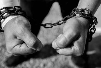 Caucasian man hand in rusty chains , shallow depth of field, conceptual image of  crime, slavery in...