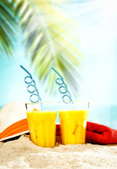 Table background with orange ice juice in a glass on a wooden table top with beautiful blue sky and ocean and palm tree view.