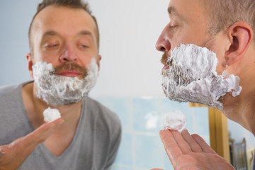 Guy shaving his beard in bathroom