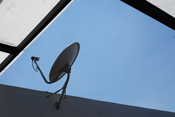Satellite dish or parabola on the wall beside roof