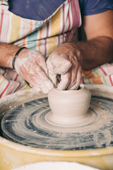 Man creating vase on a pottery wheel.