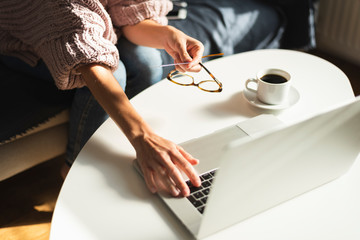 Woman working on a laptop computer while drinking coffee or tea. Online shopping. Credit cart.