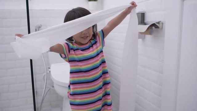 toddler pulling out toilet paper while playing around in the bathroom
