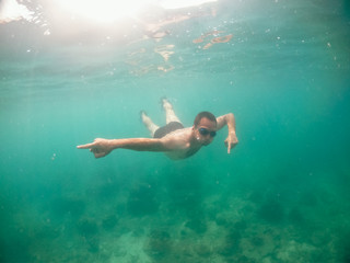 Fototapeta na wymiar Young man swimming in blue water in the ocean