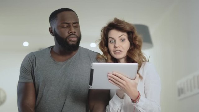 Young couple standing at living room with tablet together.