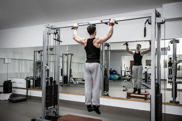 Fototapeta premium Man making some exercises on crossbar at gym