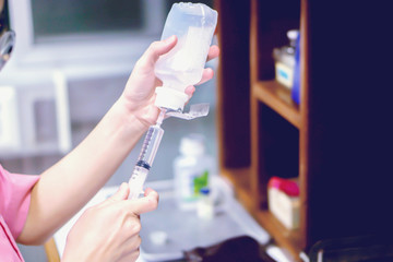 A picture of nurse hands in preparation an injection vaccine for the patient in blue light tone.