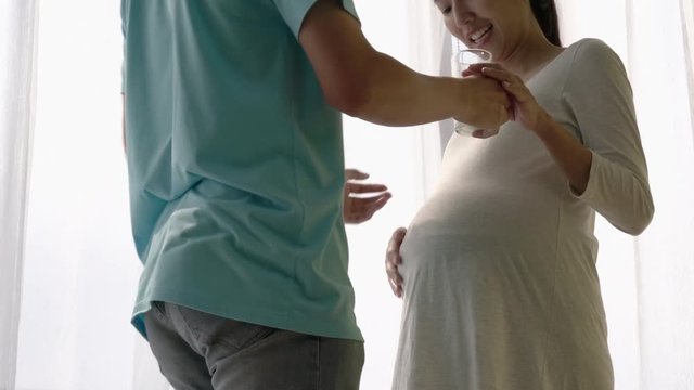 Asian family husband send milk and listening sound flex in pregnant woman belly. Children flex in the stomach. Concept of family, hope and new born.