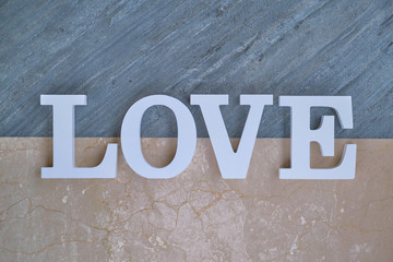 The inscription word love in white on dark and pink marble. White letters are on top of a marble slab.
