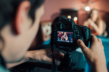 photographer shoots a beautiful model in a restaurant at the table. Girl advertises clothes. Photo and video advertising