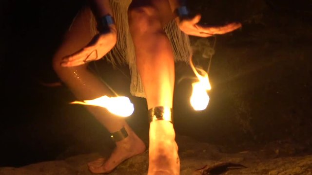 A girl in a cave holds fire dangerously through her body.