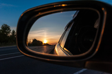 sunset in the rear view mirror of a car