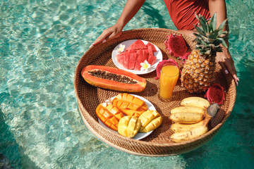 Breakfast tray in swimming pool, floating breakfast in luxury hotel smoothies and fruit plate, smoothie bowl by the hotel pool. Exotic summer diet. Tropical beach lifestyle. Bali