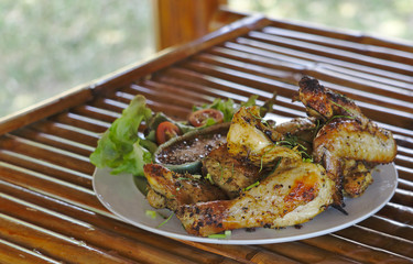 Grilled chicken and Thai style spicy sauce with organic vegetable salad in white plate on bamboo table