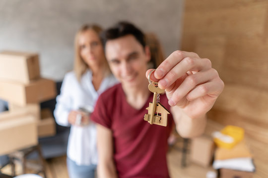 Young happy couple hugging, showing keys to new house. Family couple moving to a new apartment together. Relocation concept