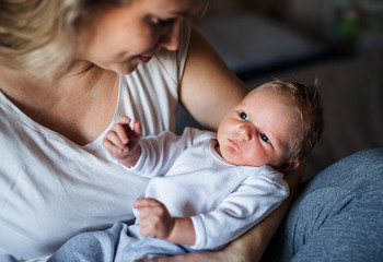 A beautiful young mother with a newborn baby at home.