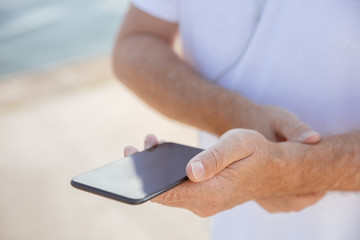 Senior man as runner with fitness tracker at the riverside. Caucasian male model using gadgets while jogging and cardio training in summer's morning. Healthy lifestyle, sport, activity concept.