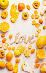 Various yellow and orange color fruits and vegetables on white table background with word love sign. Flat lay. Food layout. Color diet. Benefits of yellow and orange color food. Healthy eating.