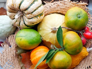  Bright ripe tangerines and pumpkins in a straw basket, concept of autumn harvest, healthy nutrition