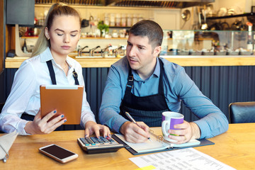 Small family restaurant owners discussing finance calculating bills and expenses of their new small business. - 281205839