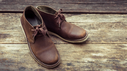 Brown stylish boots on wood background,  retro color